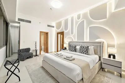 a white bedroom with a large bed and a chair at Elegant 2BR with Panoramic Marina View in Dubai