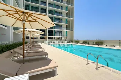 a swimming pool with chairs and umbrellas next to a building at Luxury Studio in JVC Near Marina & Downtown in Dubai