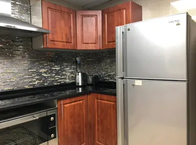 a kitchen with wooden cabinets and a stainless steel refrigerator at JLT Luxury New 2BHK in Dubai