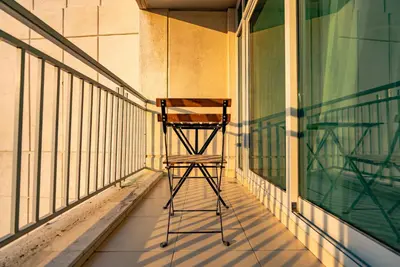 a wooden chair sitting on the side of a balcony at Grand 1bhk burj khalifa view Downtown in Dubai