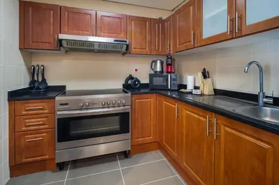 a kitchen with wooden cabinets and a stainless steel oven at Luxury JLT 1BR 2 Beds in Room Lakeview & Pool in Dubai