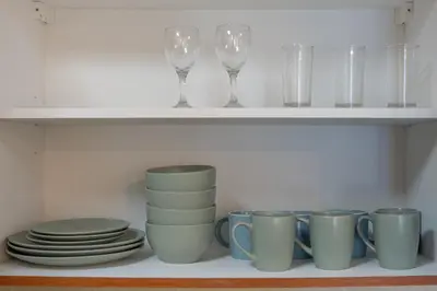 a shelf with cups and plates and wine glasses at Luxury JLT 1BR 2 Beds in Room Lakeview & Pool in Dubai