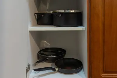 two pots and pans on a shelf in a kitchen at Luxury JLT 1BR 2 Beds in Room Lakeview & Pool in Dubai