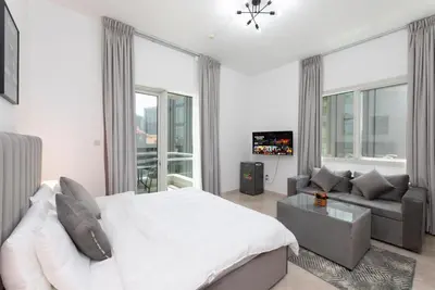 a bedroom with a bed and a couch and windows at Comfort Ensuite with Balcony in Dubai