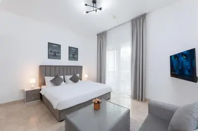 a white bedroom with a bed and a couch at Comfort Ensuite with Balcony in Dubai