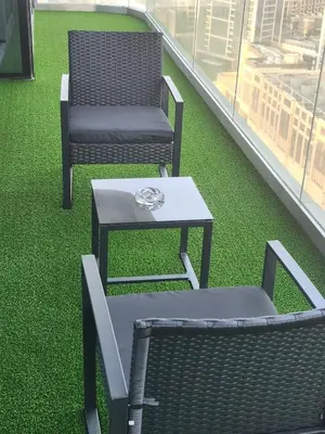 two chairs and a table on a balcony with green grass at Amazing Burj Khalifa Views with Highest Infinity pool in Dubai
