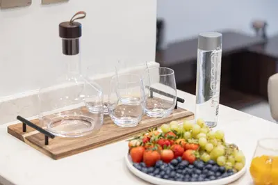 a plate of fruit and wine glasses on a counter at Deluxe Nobles Suites by Hostiva - Garden View in Dubai