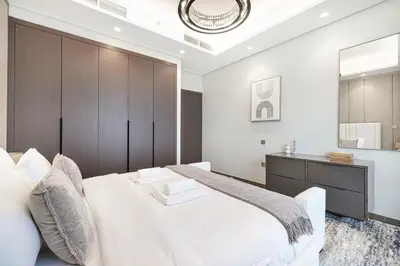 a bedroom with a large white bed and a mirror at Deluxe Nobles Suites by Hostiva - Garden View in Dubai