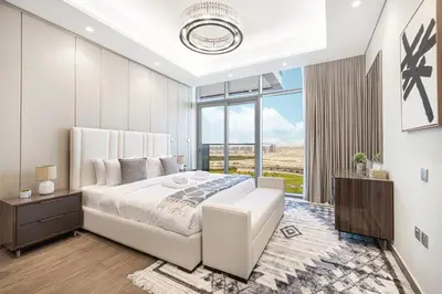 a white bedroom with a large bed and a window at Deluxe Nobles Suites by Hostiva - Garden View in Dubai