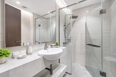 a bathroom with a sink and a glass shower at Deluxe Nobles Suites by Hostiva - Garden View in Dubai