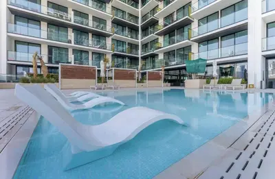 a swimming pool in front of a building at Cozy Apartment Gym and Pool Heart of JVC in Dubai