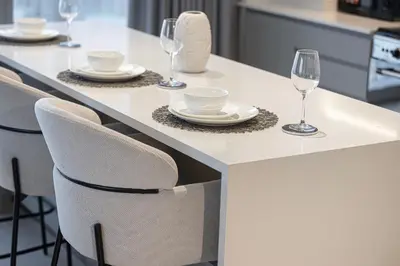 a kitchen with a white table with wine glasses at Grande Altura Burj & Fountain view 57 floor in Dubai