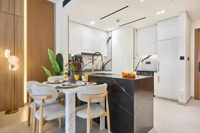 a kitchen with a table and chairs and a kitchen with white cabinets at 1BR Apartment with Private Jacuzzi & Burj Khalifa Skyline in Trillionaire Residences By Binghatti in Dubai