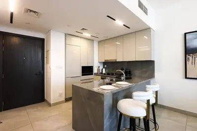 a kitchen with two bar stools and a sink at 1BR Paragon Tower Burj Khalifa & Canal Views in Dubai