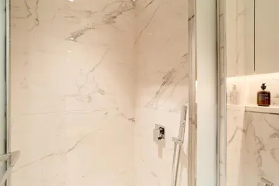 a white marble shower with a glass door at Modern & Elegant Studio Apartment in Azizi Riviera in Dubai