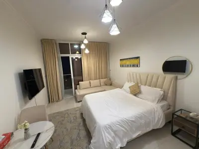 a bedroom with a large white bed and a couch at Carson Tower- A Damac Hills 1, Studio Apartment in Dubai