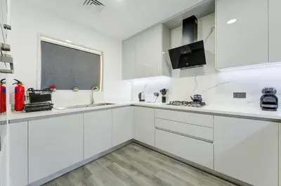 a white kitchen with white cabinets and a window at Souk Al Bahar Lavish 1-bedroom apartment with Burj Khalifa view at your doorstep by Norbu Holiday Homes in Dubai