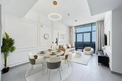a white living room with a table and chairs at Modern 2BR in Ikarus Tower, Dubai Production City in Dubai