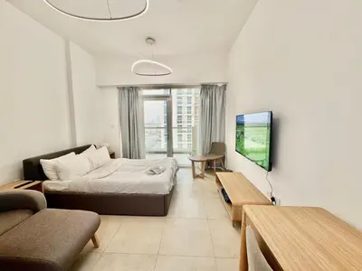 a bedroom with a bed and a couch and a tv at Homes2Retreat - Cozy Studio with Pool and Sauna in Al Furjan in Dubai