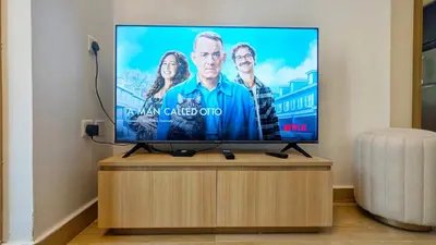a flat screen tv sitting on top of a wooden stand at Modern Apartment in Regina Tower JVC - Easy Access to JBR, Circle Mall & Dubai Hills Mall in Dubai