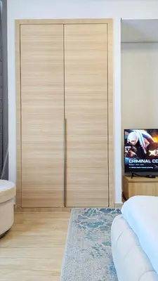 a bedroom with a large wooden closet with a tv at Modern Apartment in Regina Tower JVC - Easy Access to JBR, Circle Mall & Dubai Hills Mall in Dubai
