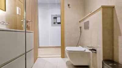 a bathroom with a toilet and a refrigerator at Modern Apartment in Regina Tower JVC - Easy Access to JBR, Circle Mall & Dubai Hills Mall in Dubai