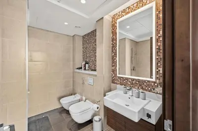 a bathroom with two sinks and a toilet and a mirror at Sobha Hartland, Green building2 1BR in Dubai
