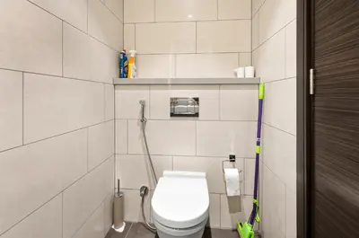 a white bathroom with a toilet and a hose at Sobha Hartland, Green building2 1BR in Dubai