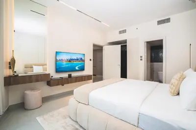 a white bedroom with a bed and a tv on a wall at Penthouse on 74th Floor 3 Bedrooms Palm Views in Dubai