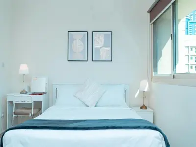 a white bedroom with a bed and a window at Bright & Spacious 2BR Apartment | The Greens Community in Dubai