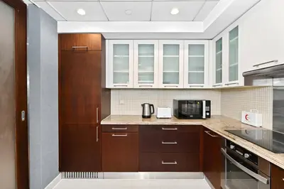 a kitchen with wooden cabinets and a microwave at Lux 1BR & Steps to Dubai Mall & Burj Khalifa in Dubai