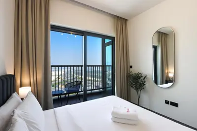a bedroom with a bed with a view of a balcony at Stylish 1BR with Skyline Views Sobha Crest, Hartland in Dubai