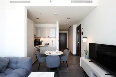 a living room with a blue couch and a table at Stylish 1BR with Skyline Views Sobha Crest, Hartland in Dubai