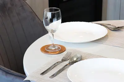 a table with white plates and a wine glass on it at Stylish 1BR with Skyline Views Sobha Crest, Hartland in Dubai