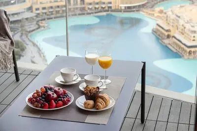a table with two glasses of orange juice and a plate of food at Luxury 4BR Burj View Steps from Dubai Mall in Dubai