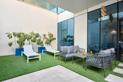 a patio with chairs and a table and grass at Palm Jumeirah Oasis - Stylish 1 Bedroom Apartment with Garden, Pool & private Beach Access in Dubai