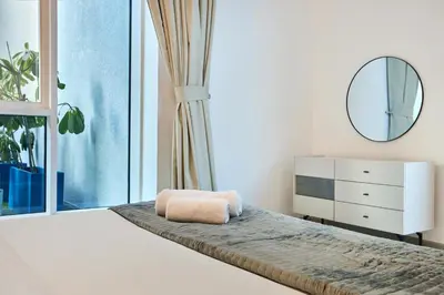a bedroom with a bed with a mirror and a window at Palm Jumeirah Oasis - Stylish 1 Bedroom Apartment with Garden, Pool & private Beach Access in Dubai