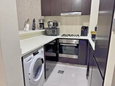 a kitchen with a stove and a washing machine at Bright & Cozy 1BR in Business Bay with Skyline Views in Dubai