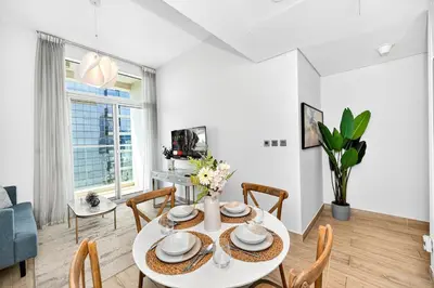 a dining room with a white table and chairs and a couch at Dubai Marina Living 1BR near JBR in Dubai