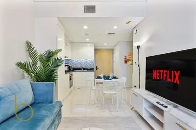 a living room with a television and a kitchen at Bookable 2 bed Damac Aykon City with Balcony & Pool access in Dubai