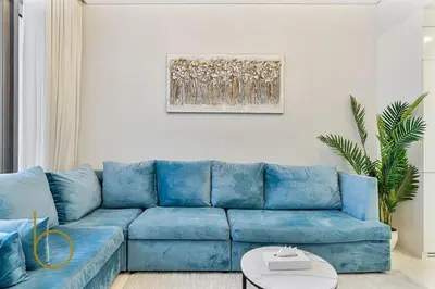 a blue couch in a living room with a painting at Bookable 2 bed Damac Aykon City with Balcony & Pool access in Dubai