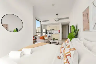 a white bedroom with a large bed and a mirror at FIRST CLASS Studio Cozy Comfort in Dubai