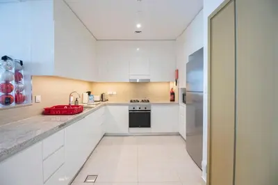 a white kitchen with a sink and a refrigerator at Downtown Views 2BR-Direct Dubai Mall Connection in Dubai