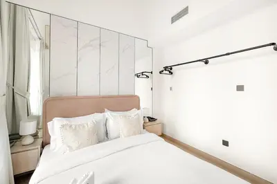 a white bedroom with a bed with white sheets and pillows at FIRST CLASS 2BR Modern Comfort in the City in Dubai