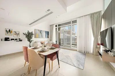 a white living room with a table and chairs at FIRST CLASS 2BR Modern Comfort in the City in Dubai
