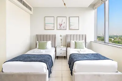two beds in a room with two windows at Silkhaus Lavish 2BDR at Sky Gardens in DIFC in Dubai