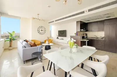 a kitchen and living room with a white table and chairs at Silkhaus Lavish 2BDR at Sky Gardens in DIFC in Dubai