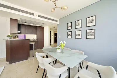 a dining room with a table and white chairs at Silkhaus Lavish 2BDR at Sky Gardens in DIFC in Dubai