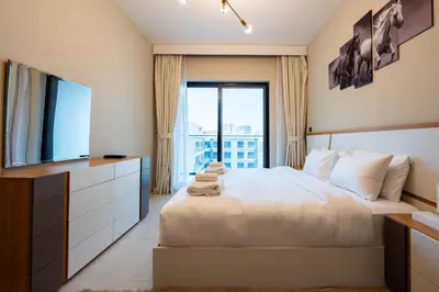 a bedroom with a large bed and a television at TRPS - Binghatti Jasmine, JVC - Pool View, Fully Furnished, Prime JVC Location in Dubai