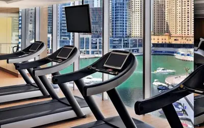 a gym with three treadmills in front of a window at The sleek in Dubai